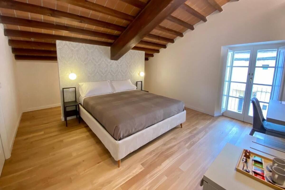 Ein Schlafzimmer mit einem Bett, Holzboden, einem Schreibtisch mit Stuhl und einem Fenster.