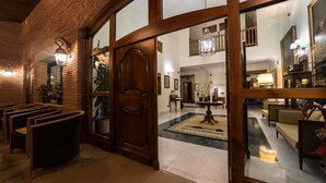 Una hall con una porta in legno, zona salotto e un lampadario.