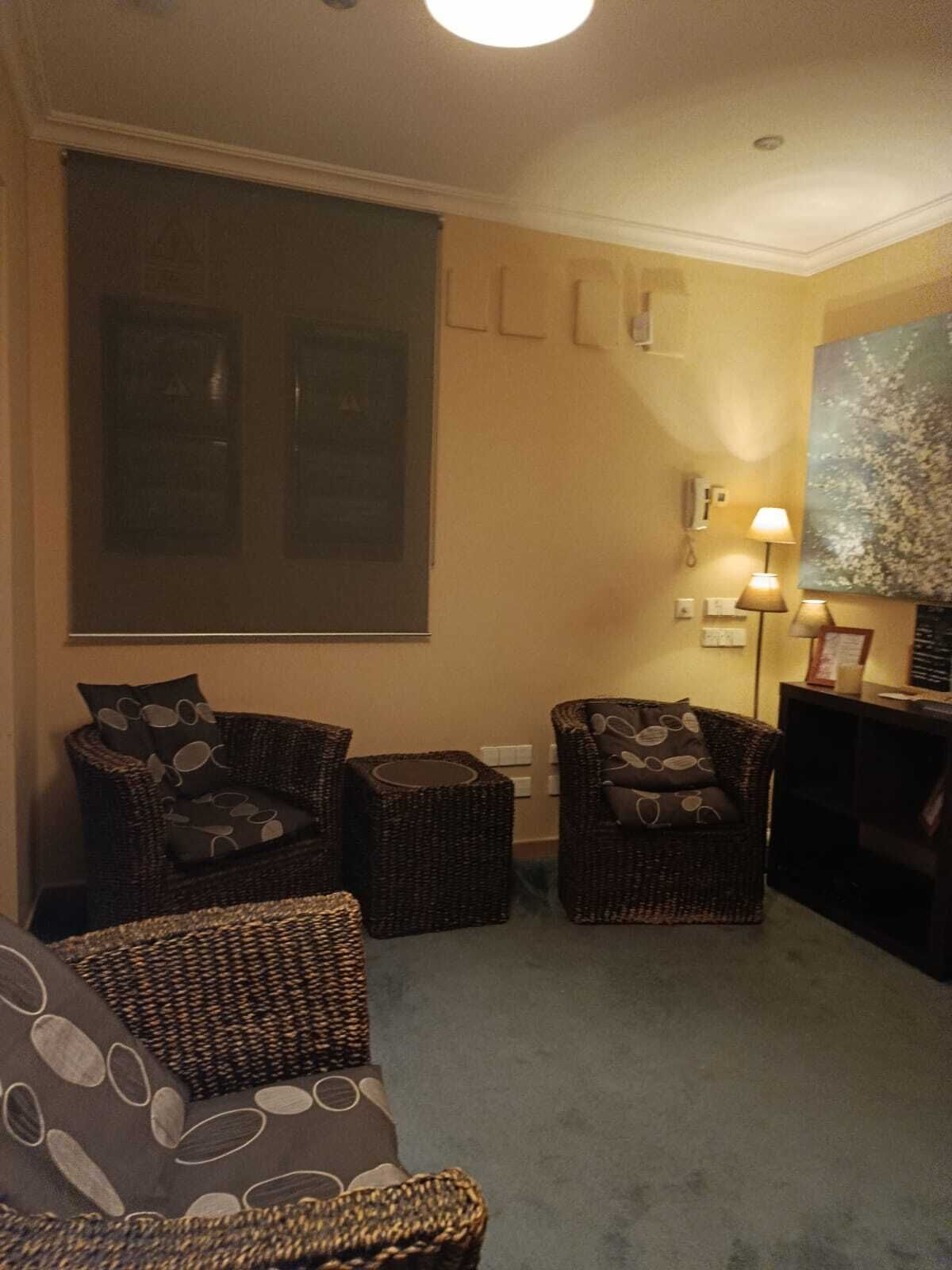 Una sala de estar con dos sillones de mimbre, una mesita y una lámpara.