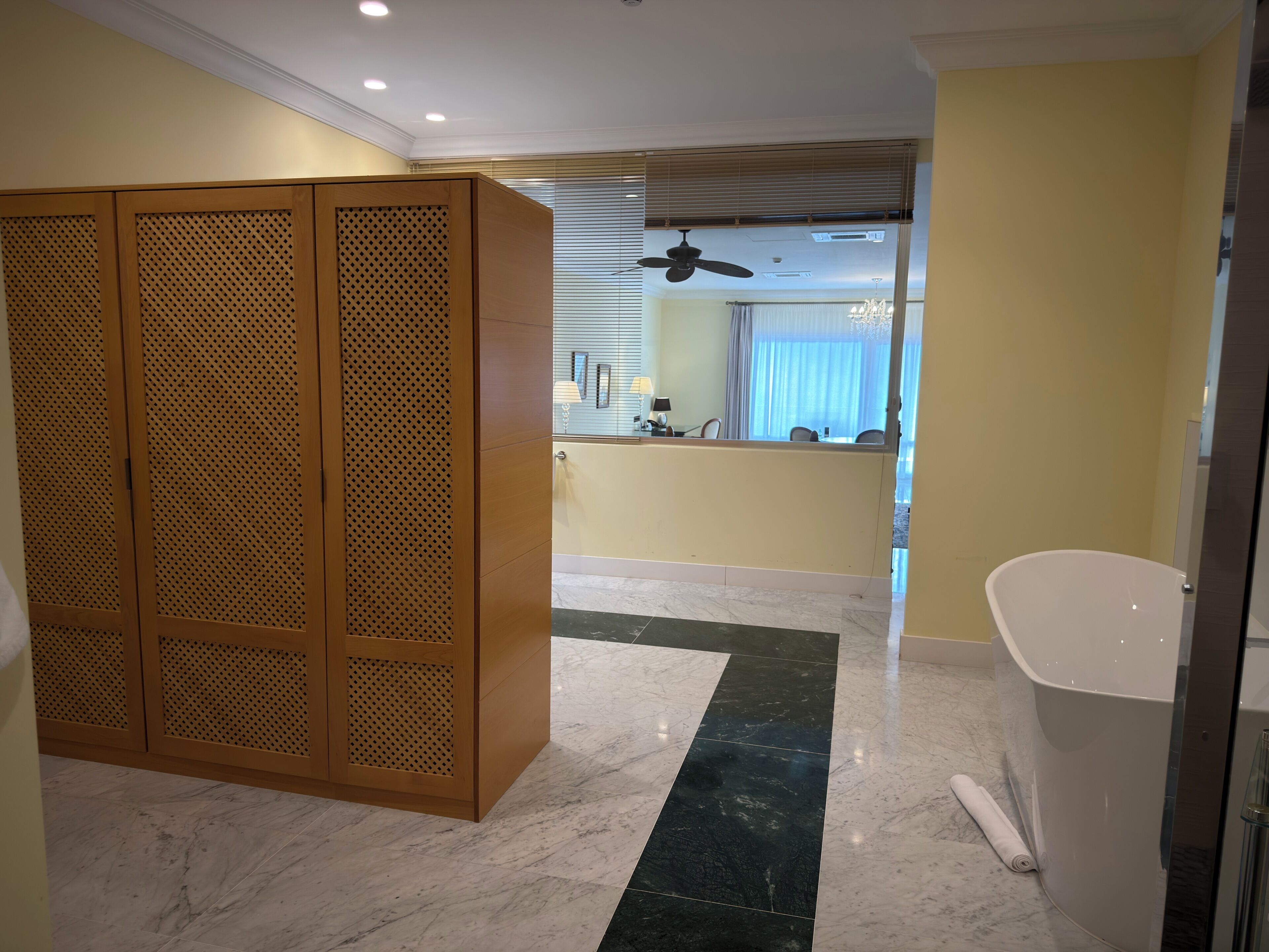 Ein Hotelzimmer mit einer Holzwand, einem Badezimmer mit einer Badewanne, einem Deckenventilator und einem Essbereich mit Blick.