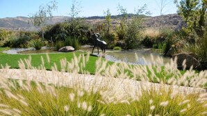 Un jardín ajardinado con fuente, una estatua y vistas a colinas distantes.