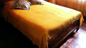 A bedroom with a wooden bed, a nightstand, a lamp, and a window with curtains. - Bello departamento en la Maravillosa ciudad de La Paz (La Paz)