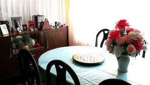 A dining area with a round table, chairs, a vase of flowers, and a window with curtains. - Bello departamento en la Maravillosa ciudad de La Paz (La Paz)