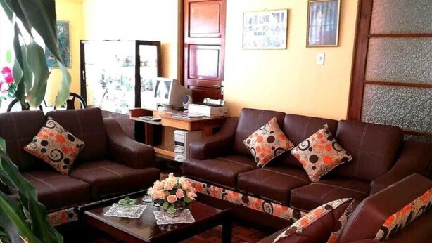 A living room with brown leather sofas, a coffee table with flowers, and a wooden floor. - Bello departamento en la Maravillosa ciudad de La Paz (La Paz)
