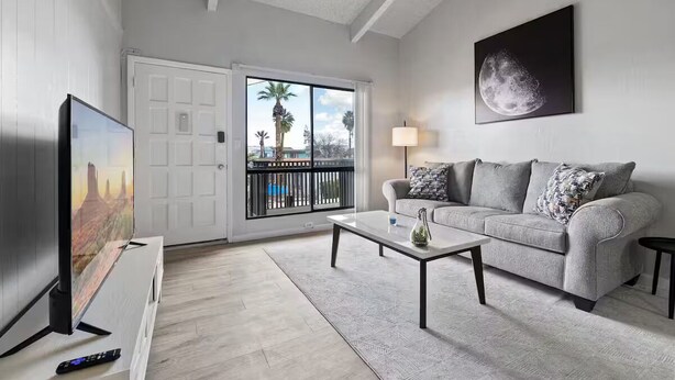 A living room with a sofa, coffee table, TV, and artwork. - Meticulously Kept Downtown Mesa 1-Bedroom Oasis (Mesa)