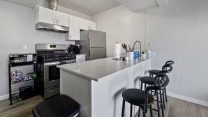 A modern kitchen with a central island, stainless steel appliances, and bar stools. - Meticulously Kept Downtown Mesa 1-Bedroom Oasis (Mesa)