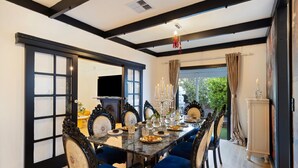 A dining room with a long table, blue upholstered chairs, and a chandelier. - Luxury Glam Pool Retreat Near Glenelg Beach-sleeps 10 (Dover Gardens)