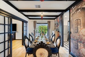 A dining room with a long table, ornate chairs, and a view of greenery outside. - Luxury Glam Pool Retreat Near Glenelg Beach-sleeps 10 (Dover Gardens)