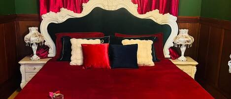 A bed with a white headboard, red and white bedding, and a chandelier.