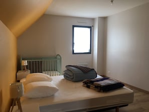 Een slaapkamer met een bed, ledikant, raam en lamp.