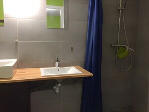Une salle de bain avec un lavabo, un miroir, une douche et un porte-serviettes vert.