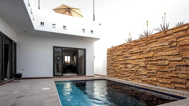 Ein moderner Poolbereich im Innenbereich mit Steinwand, klarem Becken und Glastür-Eingang.