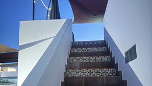Eine Treppe mit gemusterten Fliesen, eine weiße Wand und ein dunkler Sonnenschutz.