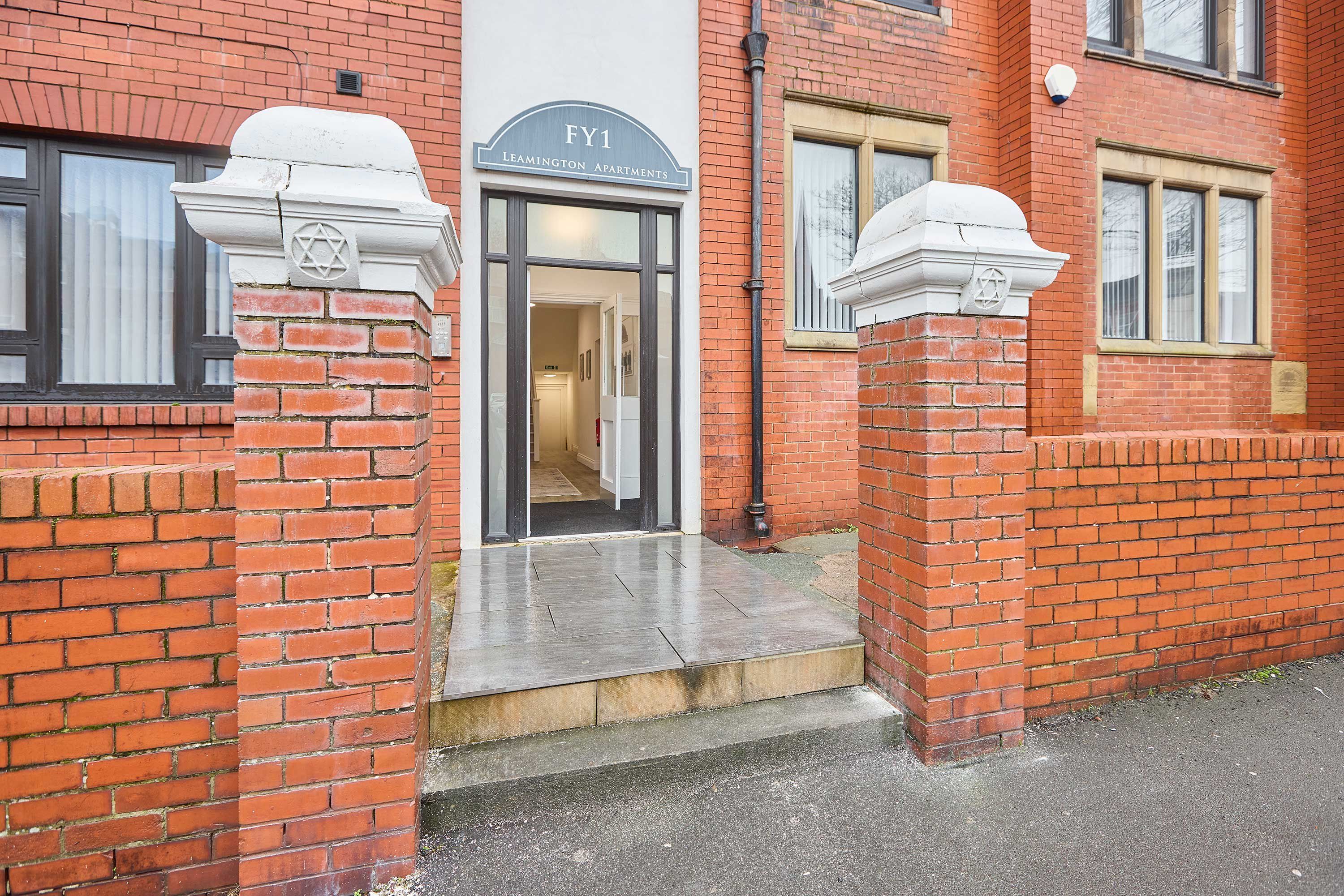 Een gebouw van baksteen met een bord waarop staat 'FY1 Leamington Apartments'.