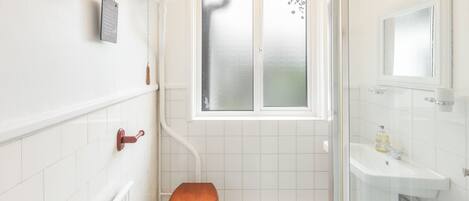A bathroom with a wooden toilet, a window, a sink, and a mirror.