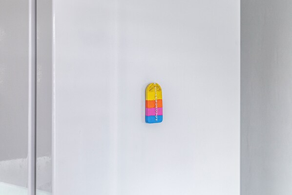 A white wall with a colorful, vertical object that appears to be a decorative item or sign. - Host Stay Elmville (Scarborough)