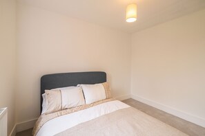A bedroom with a bed, a headboard, and a wall-mounted light fixture. - Host Stay Hawthorn Bank (Leeds)