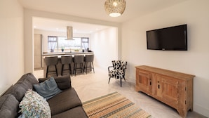 A modern living room with a sofa, a patterned rug, a wooden cabinet, and a TV mounted on the wall. - Host Stay Hawthorn Bank (Leeds)