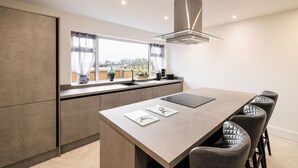 A modern kitchen with a large island, a built-in oven, and a window with curtains. - Host Stay Hawthorn Bank (Leeds)
