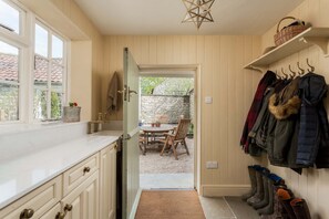 A kitchen with a window, a door leading to an outdoor patio, and a coat rack with boots. - Host Stay Corner House (York)