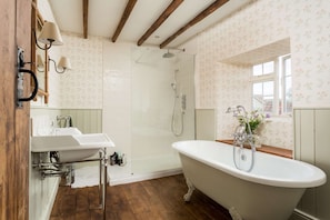 A bathroom with a clawfoot bathtub, a glass-enclosed shower, and a wooden floor. - Host Stay Corner House (York)