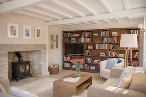 A cozy living room with a fireplace, a large bookshelf, and a comfortable sofa. - Host Stay Corner House (York)