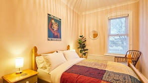 A bedroom with a bed, a nightstand, a mirror, a window, and a poster on the wall. - Host Stay Stay Salty (Saltburn-by-the-Sea)
