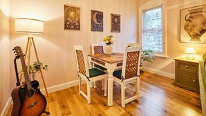 A dining area with a wooden table, four chairs, a guitar, and wall art. - Host Stay Stay Salty (Saltburn-by-the-Sea)
