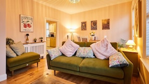 A cozy living room with a green sofa, a wooden coffee table, and a lamp. - Host Stay Stay Salty (Saltburn-by-the-Sea)