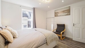 A bedroom with a bed, a chair, a window, and a door. - Host Stay Roach Street (Rochester)