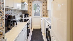 A compact kitchen with a microwave, stove, sink, and washing machine. - Host Stay Roach Street (Rochester)