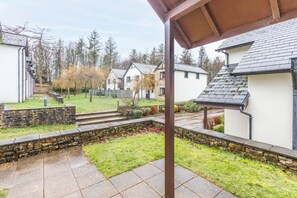 A residential area with stone walls, a grassy lawn, and houses with sloped roofs. - Host Stay 11 Troutbeck (Penrith)