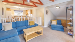 A spacious living area with a blue sofa, a wooden coffee table, and a bookshelf. - Host Stay 11 Troutbeck (Penrith)