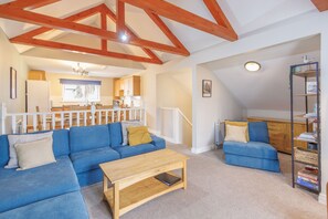 A spacious living area with a blue sofa, a wooden coffee table, and a bookshelf. - Host Stay 11 Troutbeck (Penrith)