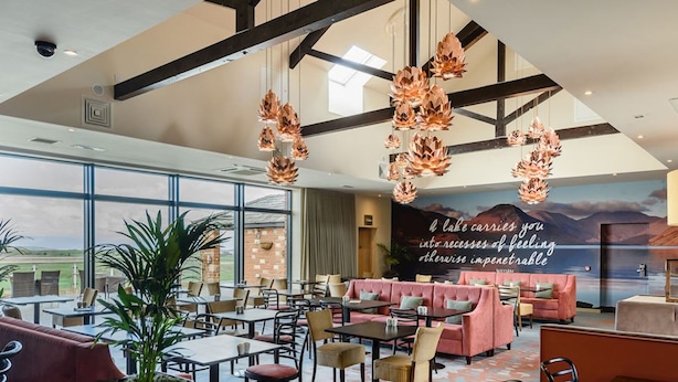 A spacious hotel lobby with a large seating area, a mural, and a view of the outdoors. - Host Stay 11 Troutbeck (Penrith)