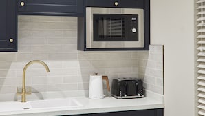 A kitchen with a stainless steel microwave, a toaster, and a modern faucet. - Host Stay Studio Temperance House (Saltburn-by-the-Sea)