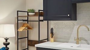A kitchen with a white countertop, a gold faucet, and a black metal shelf with a plant. - Host Stay Studio Temperance House (Saltburn-by-the-Sea)