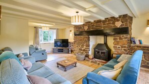 A cozy living room with a stone fireplace, sofas, a TV, and a large window. - Host Stay Morley House (Barnstaple)