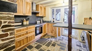 A kitchen with wooden cabinets, a stone floor, and a built-in oven. - Host Stay Morley House (Barnstaple)