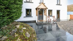 A modern building with a white exterior, a wooden porch with chairs, and a stone pathway leading to the entrance. - Host Stay Morley House (Barnstaple)