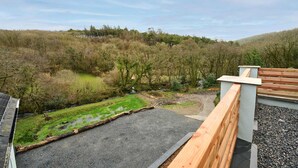 A view from a balcony overlooking a forested area with a gravel path and a small stream. - Host Stay Morley House (Barnstaple)