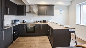 Uma cozinha moderna com armários escuros, micro-ondas, máquina de café e uma janela grande.