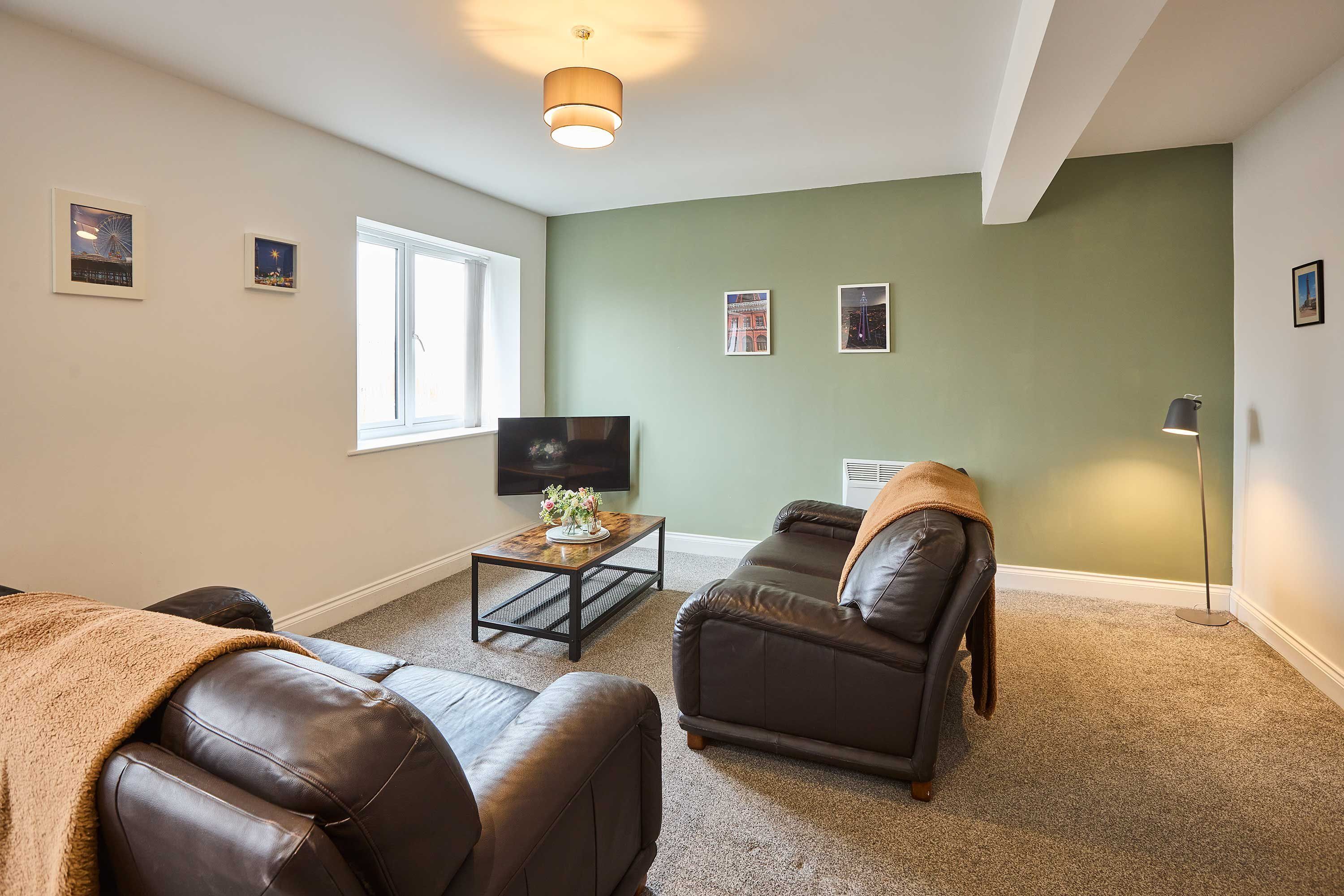 A living room with a sofa, a coffee table, a TV, and framed pictures on the wall.
