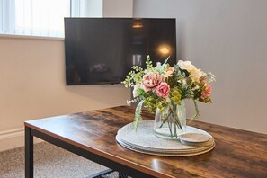 A wooden table with a vase of flowers and a placemat.