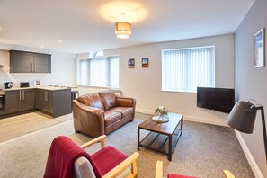 Ein modernes Wohnzimmer mit einer braunen Ledersofa, einem Holztisch und einem Fernseher.