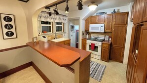 A kitchen with wooden cabinets, a microwave, a stove, and pendant lights.