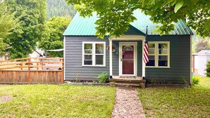 A small house with a green roof, a front door, and an American flag.