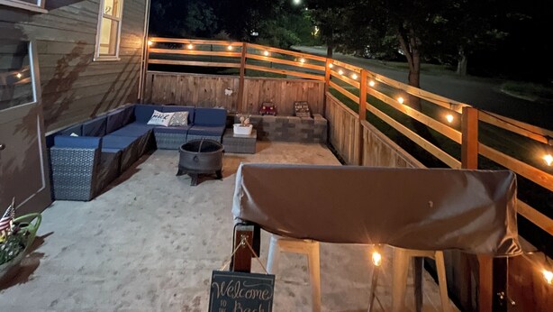 A covered outdoor seating area with a sofa, a table, and a sign that reads 'Welcome to the Back Porch.'