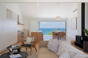 A modern living room with a sofa, dining table, and kitchen area.