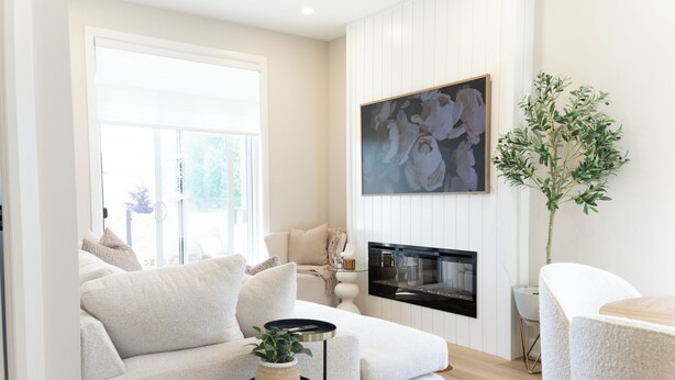 A living room with a sofa, a side table with a plant, a fireplace, and a painting on the wall.